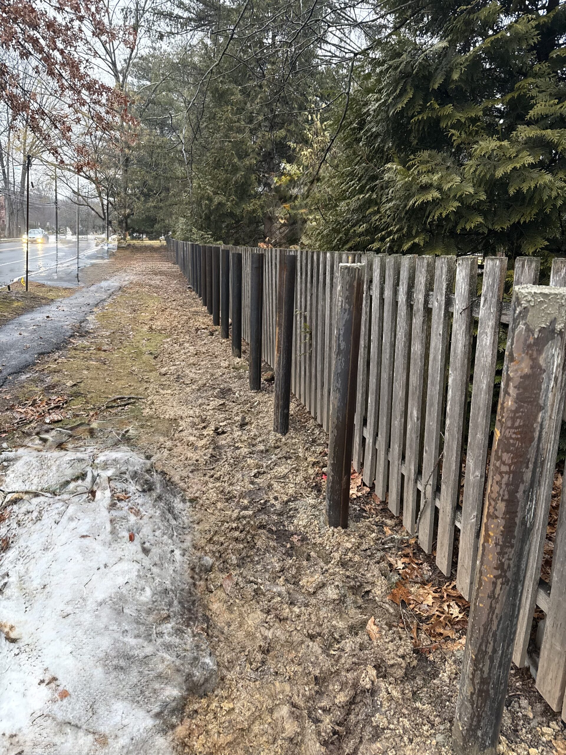 steel security bollards installed in a commercial property in front of a wooden fence, providing vehicle impact protection for a campground.